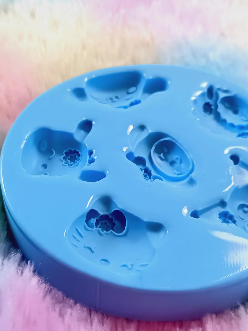 May include: Blue silicone mold with six cavities shaped like cartoon characters. The mold is designed for making small resin crafts.