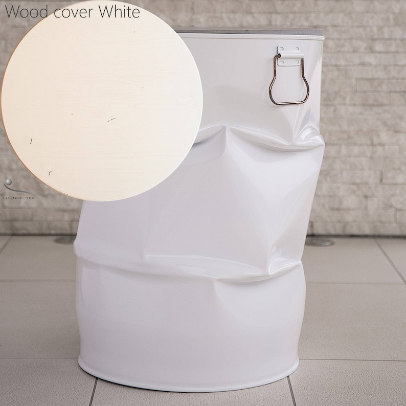 May include: A white metal barrel-shaped container with a wooden lid. The lid is round and light-colored, with the text "Wood cover White" above it. The container has a metal handle and a slightly crumpled appearance.
