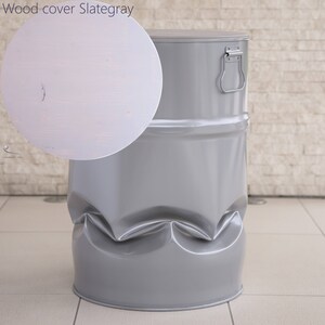May include: A gray metal drum with a matching lid and a silver handle. The drum has a unique, textured design around the base. The lid is a light gray wood cover. The text "Wood cover Slategray" is in the upper left corner.