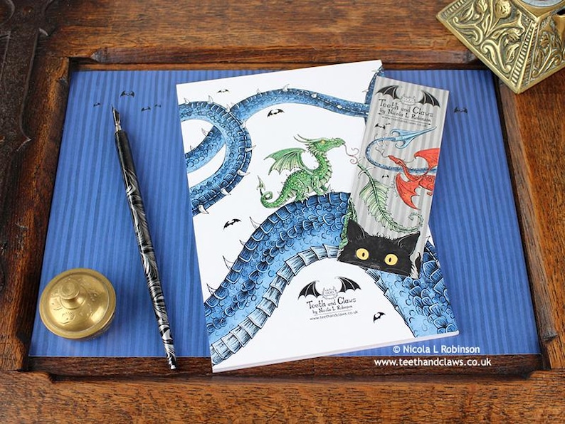 Blue Dragon Notebook featuring my original pen and ink dragon illustration, back cover, shown with bookmark and vintage Victorian writing desk accessories. Made in the UK. Design and illustration © Nicola L Robinson | Teeth and Claws