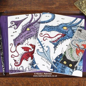 Blue Dragon Notebook featuring my original pen and ink dragon illustrations, alongside my Purple Dragon Notebook, with vintage Victorian writing desk accessories. Made in the UK. Design and illustration © Nicola L Robinson | Teeth and Claws