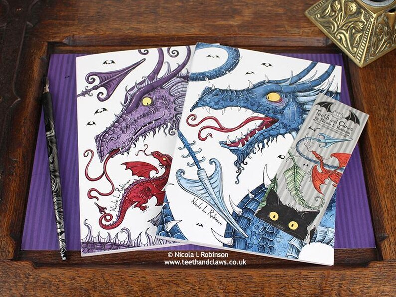 Blue Dragon Notebook featuring my original pen and ink dragon illustrations, alongside my Purple Dragon Notebook, with vintage Victorian writing desk accessories. Made in the UK. Design and illustration © Nicola L Robinson | Teeth and Claws