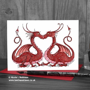 May include: A greeting card featuring a red and pink illustration of two dragons facing each other with their tails intertwined to form a heart shape. The card is blank inside for writing a message.