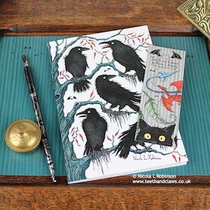 Gothic Crows Notebook featuring my original pen and ink crow illustration, front cover, shown with bookmark and vintage Victorian writing desk accessories. Made in the UK. Design and illustration © Nicola L Robinson | Teeth and Claws