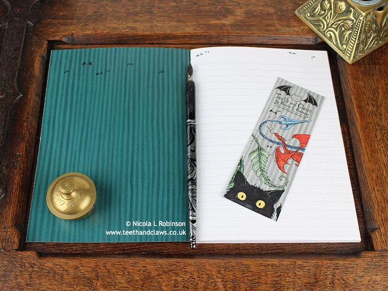 Gothic Crows Notebook, featuring my original pen and ink crow illustration, inside cover open and ready to write in, shown with bookmark and vintage Victorian writing desk accessories. Made in the UK. Design and illustration © Nicola L Robinson | Teeth and Claws