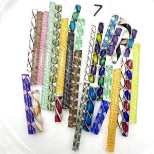 May include: A selection of patterned glass rods in a variety of colours. The rods display diverse designs, including spirals and geometric shapes, with hues of red, green, blue, yellow, and purple. The number 7 is written in black marker.