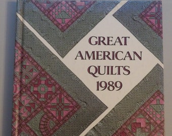 Könnte beinhalten: Ein Buchcover mit weißem Hintergrund und dem Titel "Great American Quilts 1989". Das Cover zeigt ein Patchwork-Design aus rosa und grünen Quadraten und Rauten.