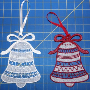 May include: Two white lace Christmas bells with red ribbon hangers. The bell on the left is white and the bell on the right is red.