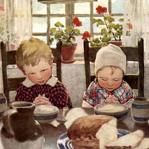 Op de afbeelding: Twee kinderen, een jongen en een meisje, zitten aan een tafel met hun handen gevouwen in gebed. Ze dragen geruite shirts en hebben kommen met eten voor zich. Een brood ligt op een blauw-wit bord in het midden van de tafel. De tafel is gedekt met een kan, een kom en een kopje. De afbeelding is in vintage stijl.