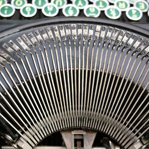 May include: Close-up of a vintage typewriter with metal keys arranged in a semi-circle. The keys are labeled with letters, numbers, and symbols.