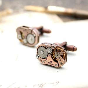 May include: A pair of cufflinks made from antique watch parts. The cufflinks are rose gold colored and feature intricate gears and a 17 jewels inscription.
