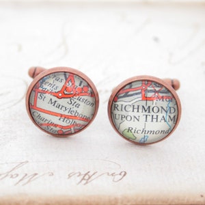 May include: A pair of copper cufflinks with vintage map designs. One cufflink features a map of London with the text "St Marylebone" and "Euston Sta". The other cufflink features a map of Richmond Upon Thames with the text "Richmond Upon Tham".