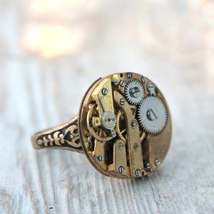 Chevalière gothique unique : fabriquée à la main avec un mouvement de montre en or et un bracelet gravé dans une ambiance steampunk