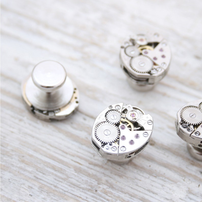 May include: Four silver cufflinks with intricate clockwork designs. Each cufflink features a different arrangement of gears and cogs, creating a unique and stylish look.