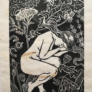 May include: Black and white woodcut print of a nude woman kneeling in a field of flowers. The print is titled "medicine" and numbered 2/100.