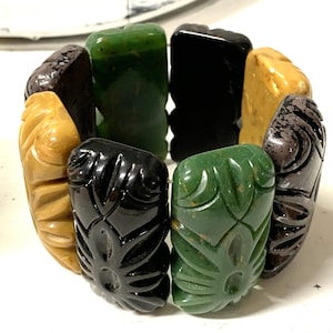 May include: A vintage carved plastic bracelet with alternating black, green and yellow rectangular links. The links have a floral design.