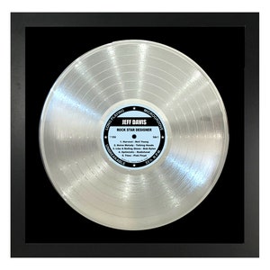 May include: A silver record with a black frame. The record has the text "LONG PLAYING" and "MICROGROOVE" on the top and bottom of the label. The label also has the text "JEFF DAVIS" and "ROCK STAR DESIGNER". The record is a platinum record.