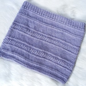 Puede incluir: Un cuello de punto de color lavanda con un patrón texturizado. El cuello está hecho de hilo suave y tiene un diseño simple y elegante.
