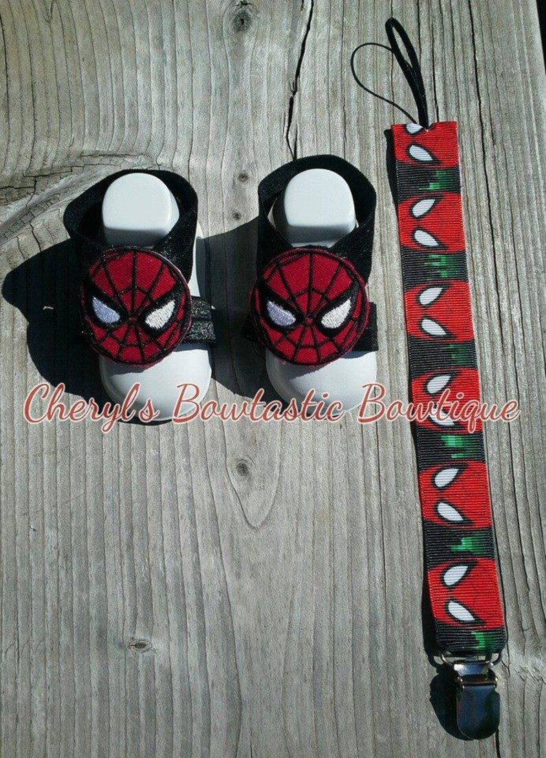 May include: A pair of baby sandals with a black strap and a red and black Spider-Man applique. A matching red, black, and white Spider-Man themed pacifier clip is also included.