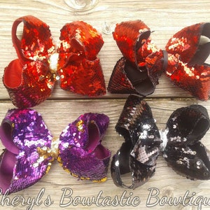 May include: Four large, sparkly hair bows in red, purple, black, and black with silver sequins. The bows are made with a soft, velvet-like material and have a large, centered sequin.