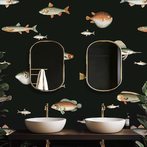 May include: A bathroom with a dark green wall adorned with illustrations of various fish. Two oval gold-framed mirrors hang above white vessel sinks with gold faucets. A dark wood vanity holds the sinks and towels.