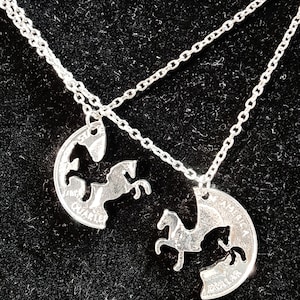 May include: Two silver necklaces with matching pendants. Each pendant is a half-circle cut from a US quarter coin, with a horse silhouette cut out. The two pendants fit together to form a complete horse.
