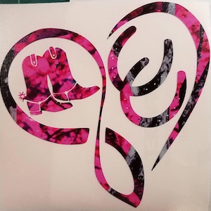 May include: Pink and black camouflage heart design with two pink cowboy boots and two black horseshoes.