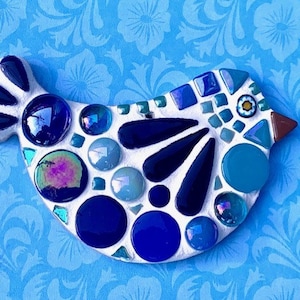May include: A blue and white mosaic bird ornament. The bird is made of small glass tiles in shades of blue, white, and brown. The bird has a round body and a long, thin beak.
