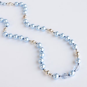 May include: A light blue pearl necklace with silver and gold beads and crystal accents.