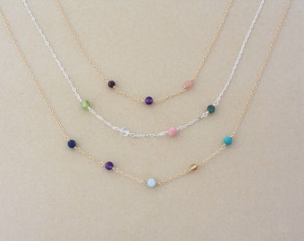 May include: Three layered necklaces with different colored beads. The top layer has pink, purple, and green beads. The middle layer has clear and pink beads. The bottom layer has blue, purple, light blue, and gold beads.