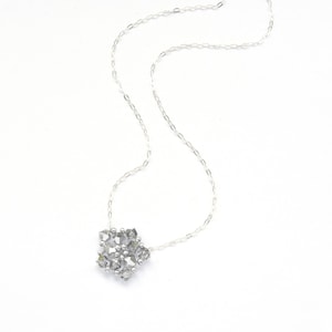 May include: A silver chain necklace with a snowflake pendant made of small, clear crystals.