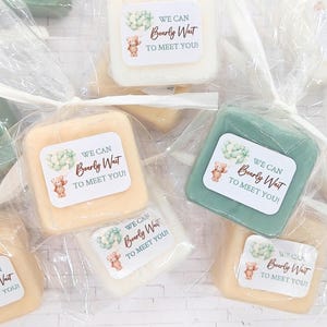 May include: Square-shaped soaps in various colors, including white, yellow, and green, are individually wrapped in clear plastic. Each soap has a sticker with a teddy bear illustration and the text "WE CAN Bearly Wait TO MEET YOU!"