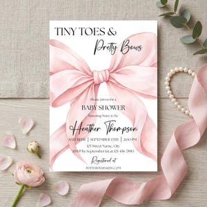 Puede incluir: Una invitación a un baby shower con un gran lazo rosa de acuarela. El texto dice "Tiny Toes & Pretty Bows" e incluye detalles del evento, como la fecha, la hora y el lugar. La invitación está decorada con detalles florales.