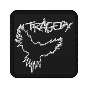 May include: Black embroidered patch with a white outline of a bird and the word "TRAGEDY" in white.