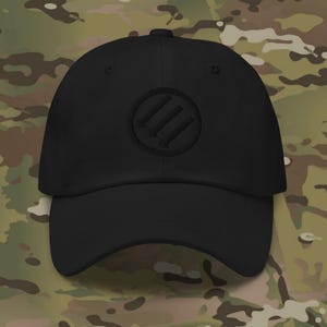 May include: Black baseball cap with a curved brim and a circular emblem featuring three vertical lines. The cap is made of a durable fabric and has a classic, adjustable design. The hat is a solid black color.