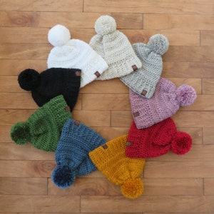 Op de afbeelding: Assortiment van acht gebreide mutsen met pompoenen in verschillende kleuren, waaronder zwart, wit, beige, groen, blauw, rood en roze.