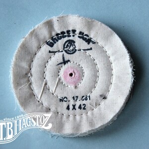 May include: A white cotton buffing wheel with a pink center hole and black text that reads "Bridget  Mfg.  No. 17.681 4 x 42 since 1898 TB Hagstoz"