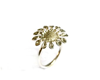 Könnte beinhalten: Ein silberner Ring mit einem Blumendesign. Die Blume hat eine strukturierte Mitte und Blütenblätter, die nach außen strahlen.
