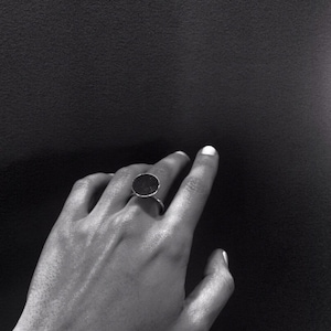 May include: A silver ring with a large, round, black stone.