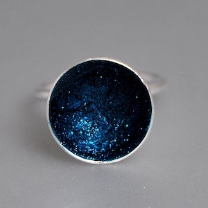 May include: A silver ring with a round blue glitter resin inlay.