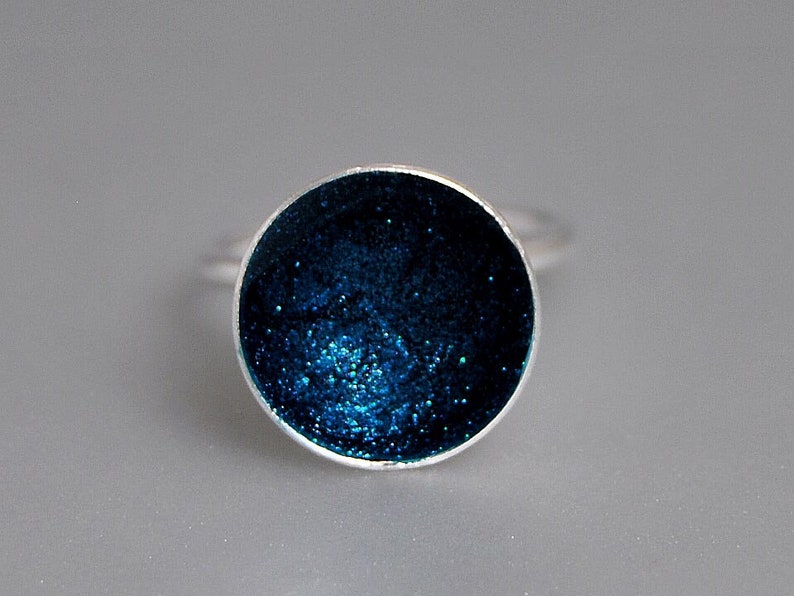May include: A silver ring with a round blue glitter resin inlay.