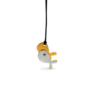 Puede incluir: Un collar con un colgante de pez de oro y plata en un cordón negro.