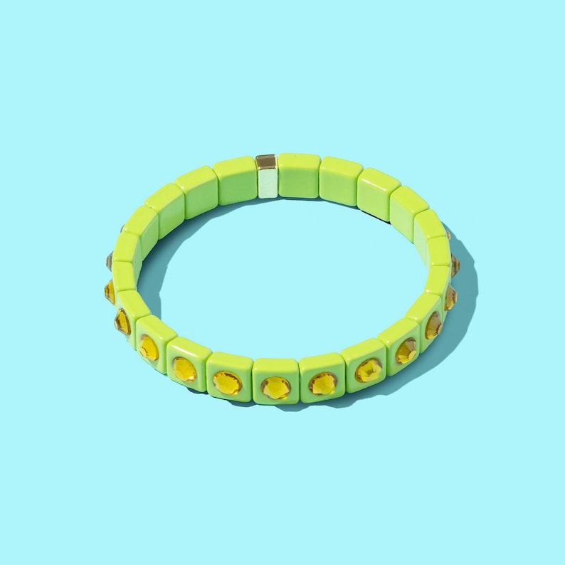 May include: A green bracelet with yellow rhinestones. The bracelet is made of square beads.