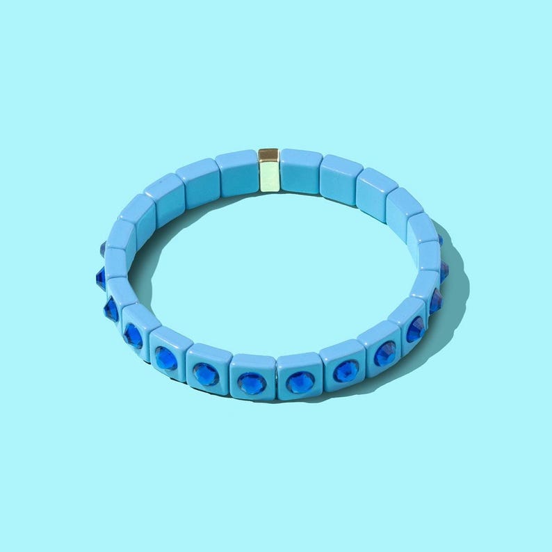May include: A light blue bracelet with a gold accent and blue gemstone accents.