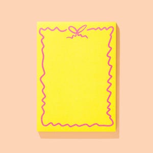 Op de afbeelding: Een gele sticky note met een roze gegolfde rand en een roze strik bovenaan.