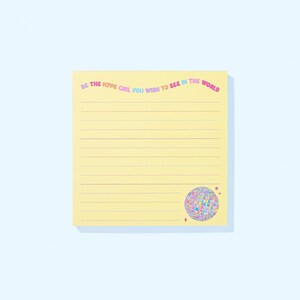 May include: A yellow lined notepad with the text "BE THE HYPE GIRL YOU WISH TO SEE IN THE WORLD" in pink, blue, and green. A colorful disco ball graphic is in the bottom right corner. The notepad is on a light blue background.