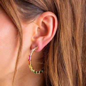 May include: Gold hoop earrings with a rainbow of colourful baguette-shaped stones.