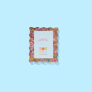 May include: A colorful confetti picture frame with a scalloped edge. The frame holds a 2" x 3" photo and features the text "FOR FUN" in bright colors. The frame is set against a light blue background.