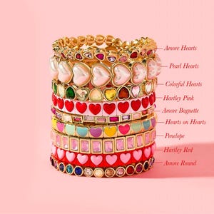 Könnte beinhalten: Ein Stapel bunter Armbänder mit Herz- und Edelstein-Designs. Die Armbänder umfassen die Stile "Amore Hearts", "Pearl Hearts", "Colorful Hearts", "Hartley Pink", "Amore Baguette", "Hearts on Hearts", "Penelope", "Hartley Red" und "Amore Round".