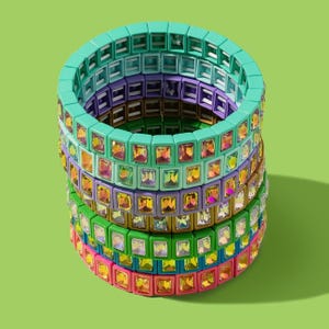 May include: A stack of colorful bracelets made of square beads. The bracelets are layered in a rainbow pattern, with shades of green, blue, purple, and pink.